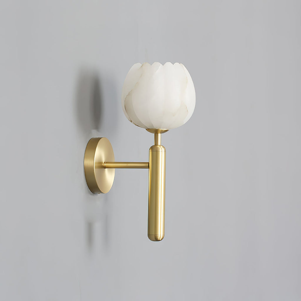 Angled view of the brass Clérachic alabaster wall sconce on a plain grey wall, the lit cup shade casting a soft shadow.