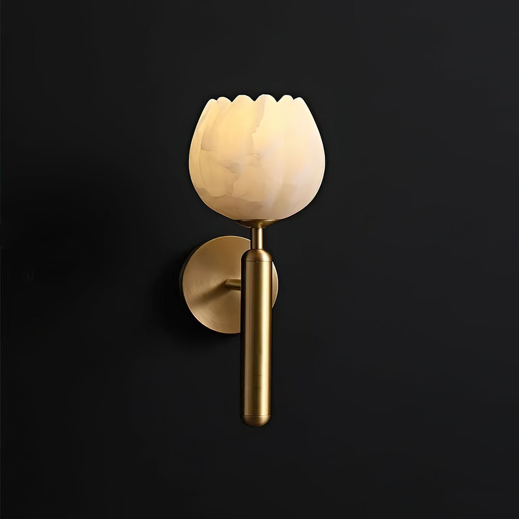Brass Clérachic alabaster wall sconce photographed against black, the lit tulip shade glowing warm above its baton.
