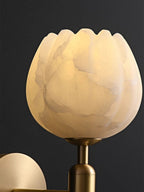 Close-up of the Clérachic alabaster wall sconce shade, its scalloped rim and grey-amber veining lit from within.