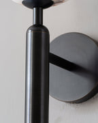 Detail of the Clérachic alabaster wall sconce in black, the gunmetal baton meeting the arm and round wall plate.