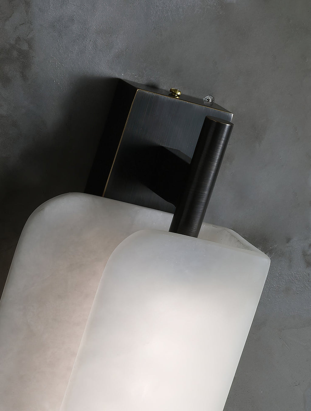 Clérachic Alabaster Wall Sconce seen from above, its dark bronze wall bracket and rod meeting the rounded top of the stone plates.