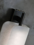 Clérachic Alabaster Wall Sconce seen from above, its dark bronze wall bracket and rod meeting the rounded top of the stone plates.