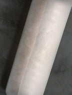 Detail of the Clérachic Alabaster Wall Sconce plates, warm cloudy veining running the length of the natural stone against a concrete wall.