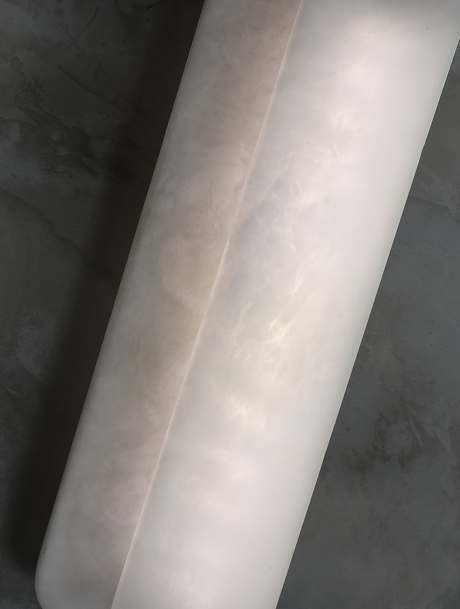 Detail of the Clérachic Alabaster Wall Sconce plates, warm cloudy veining running the length of the natural stone against a concrete wall.