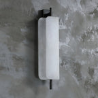The Clérachic Alabaster Wall Sconce against grey plaster, 52 cm tall and standing just 12 cm off the wall so it clears a passing shoulder.