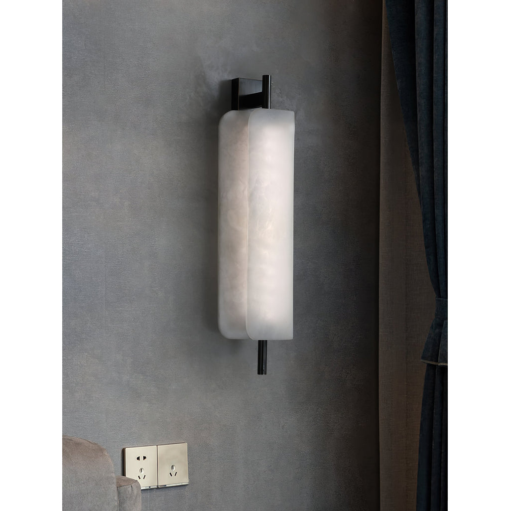 Clérachic Alabaster Wall Sconce lit on a grey concrete wall beside a curtain, sitting shallow enough to clear a bedside table.