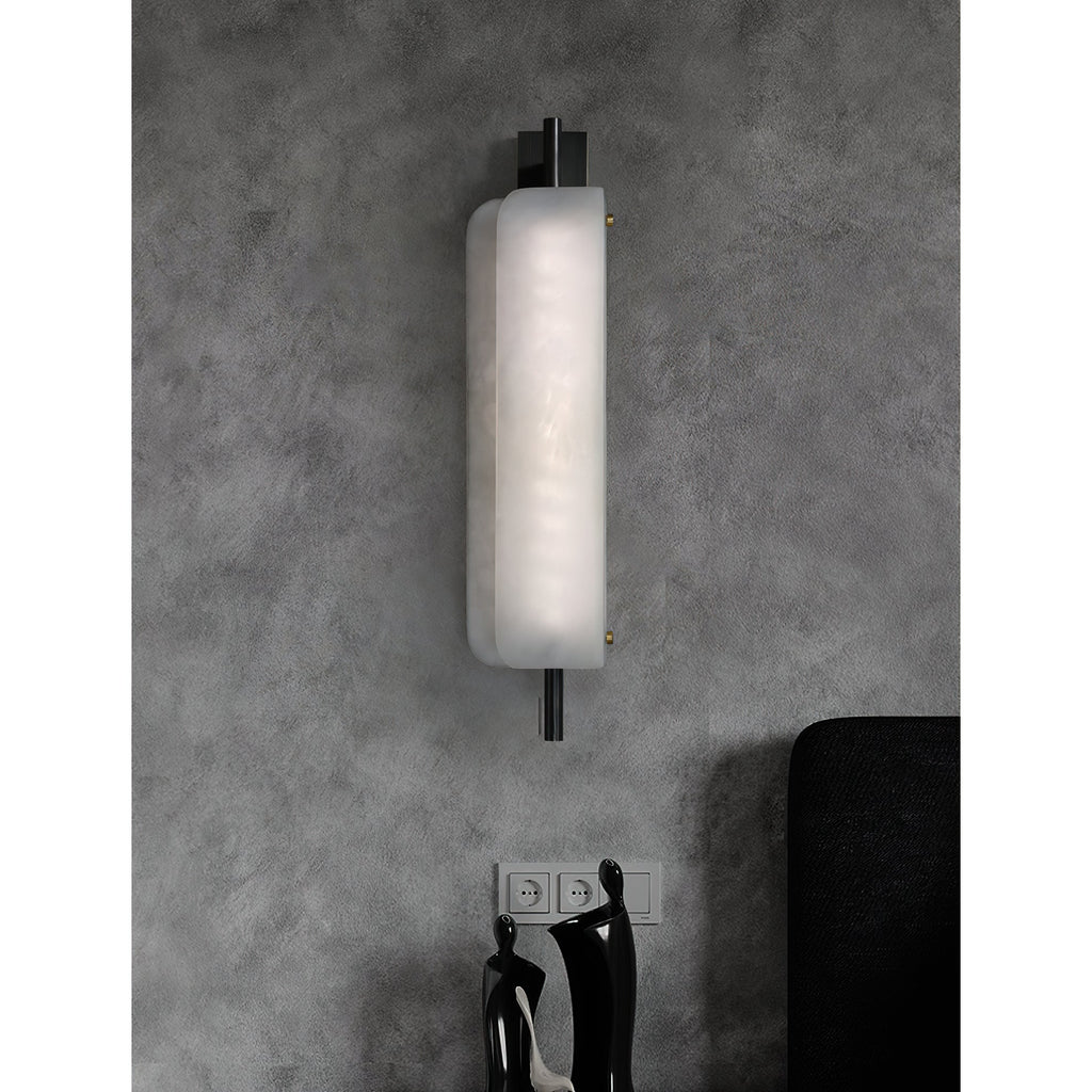 Clérachic Alabaster Wall Sconce lit above a pair of dark figurines, the offset plates sending light up the wall and down over what sits below.