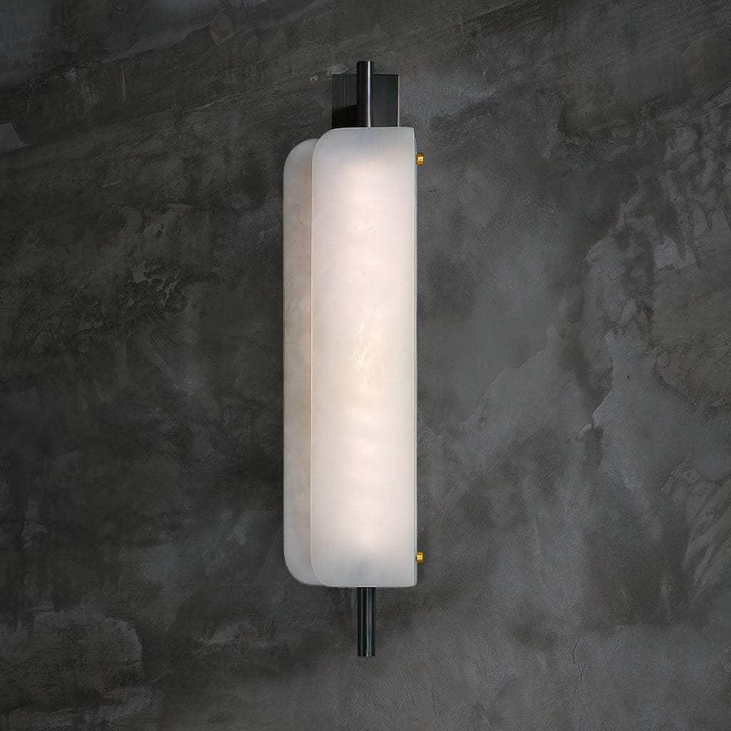 Clérachic Alabaster Wall Sconce lit against a dark concrete wall, the alabaster face even and bright from the rod above to the rod below.