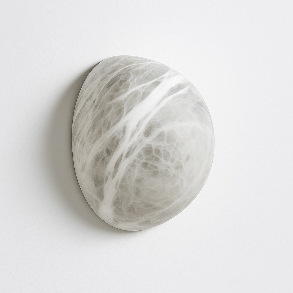 Clérachic pebble-shaped alabaster wall sconce in soft white with grey veining, mounted flat on a pale studio wall.