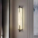 Glowing softly on a grey panelled wall, a Clérachic alabaster wall light shows its veined stone and black frame beside a pale abstract painting.