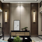 Two Clérachic alabaster wall lights flank a framed ink drawing above a console in a wood-panelled living room.