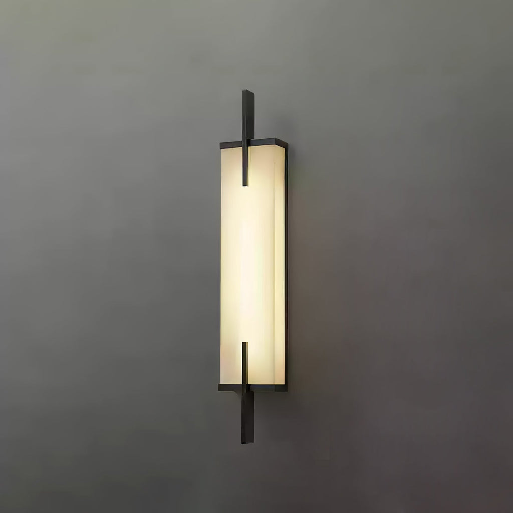 Front view of this lit Clérachic alabaster wall light with a black frame and crossing bars, on a plain dark grey wall.