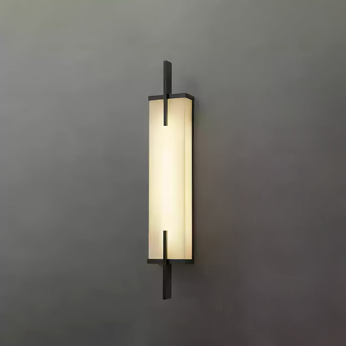 Front view of this lit Clérachic alabaster wall light with a black frame and crossing bars, on a plain dark grey wall.