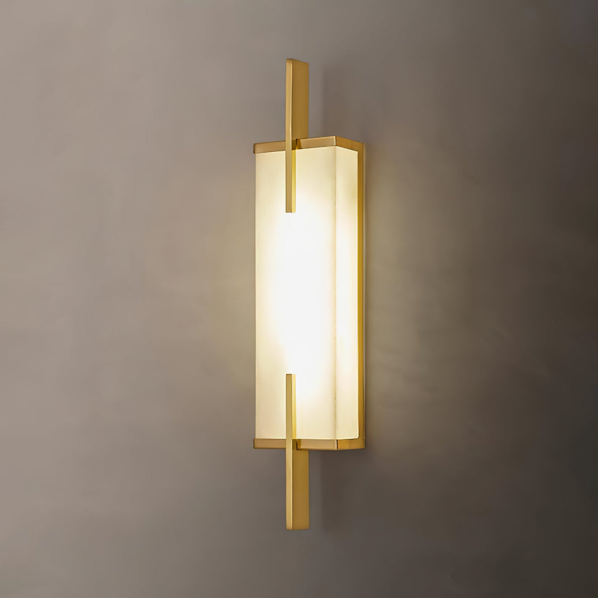Close view of this Clérachic wall light with a gold-toned frame, its alabaster panel glowing warmly on a taupe wall.