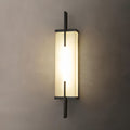 Close view of this Clérachic alabaster wall light with a black frame, glowing warmly on a taupe wall.