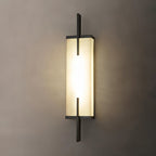 Close view of this Clérachic alabaster wall light with a black frame, glowing warmly on a taupe wall.