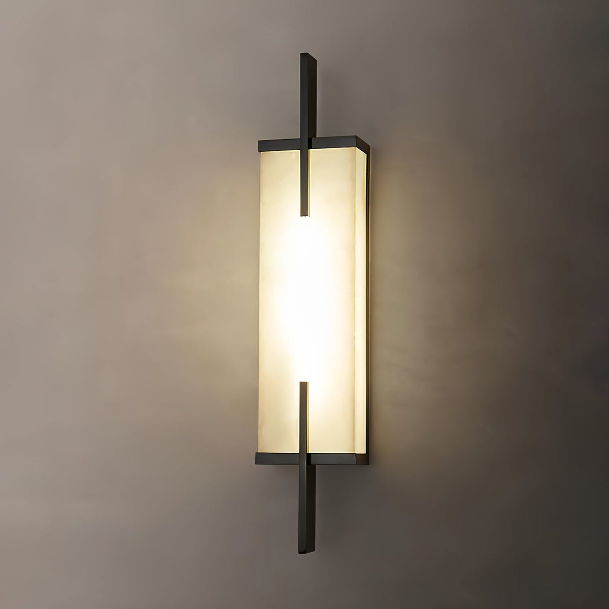 Close view of this Clérachic alabaster wall light with a black frame, glowing warmly on a taupe wall.