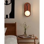 Oval Clérachic Alabaster Wall Sconce lit beside a bed, throwing a warm pool of light over the nightstand and a vase of flowers.