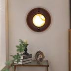 Clérachic Alabaster Wall Sconce lighting a narrow hall wall above a console stacked with books and a small gilt frame.