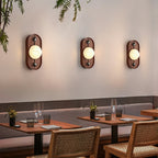 Three oval Clérachic Alabaster Wall Sconce fittings in a row above restaurant banquette seating, each washing the wall with warm light.