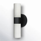 The Clérachic Alight sconce in black, angled to show how the disc backplate holds the alabaster tube off the wall.