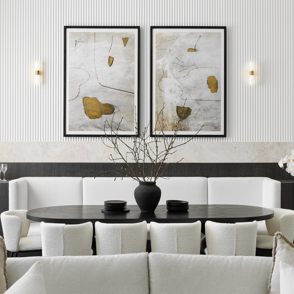 Clérachic Alight sconces flanking two framed artworks above a pale banquette in a fluted-panel dining room.