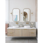 Clérachic Alight sconces on a panelled bathroom wall, glowing between slim mirrors above a floating timber vanity.