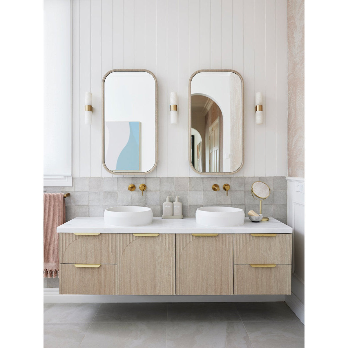 Clérachic Alight sconces on a panelled bathroom wall, glowing between slim mirrors above a floating timber vanity.