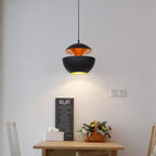 Black and gold bowl pendant lit above a small wooden table with a framed sign and a basket of flowers, from Clérachic.