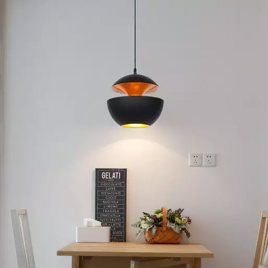 Black and gold bowl pendant lit above a small wooden table with a framed sign and a basket of flowers, from Clérachic.