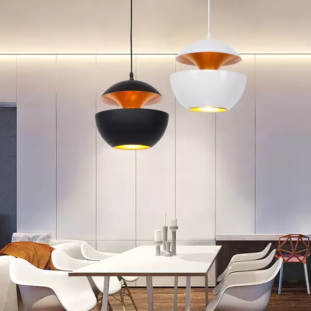 A black and a white Clérachic pendant hung side by side above a white dining table with moulded chairs.