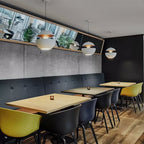 Several white pendants with gold interiors hung above café tables with yellow and black chairs, lamps from Clérachic.