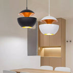 Black and white Clérachic pendants with gold interiors hang together beside wooden kitchen cabinets.