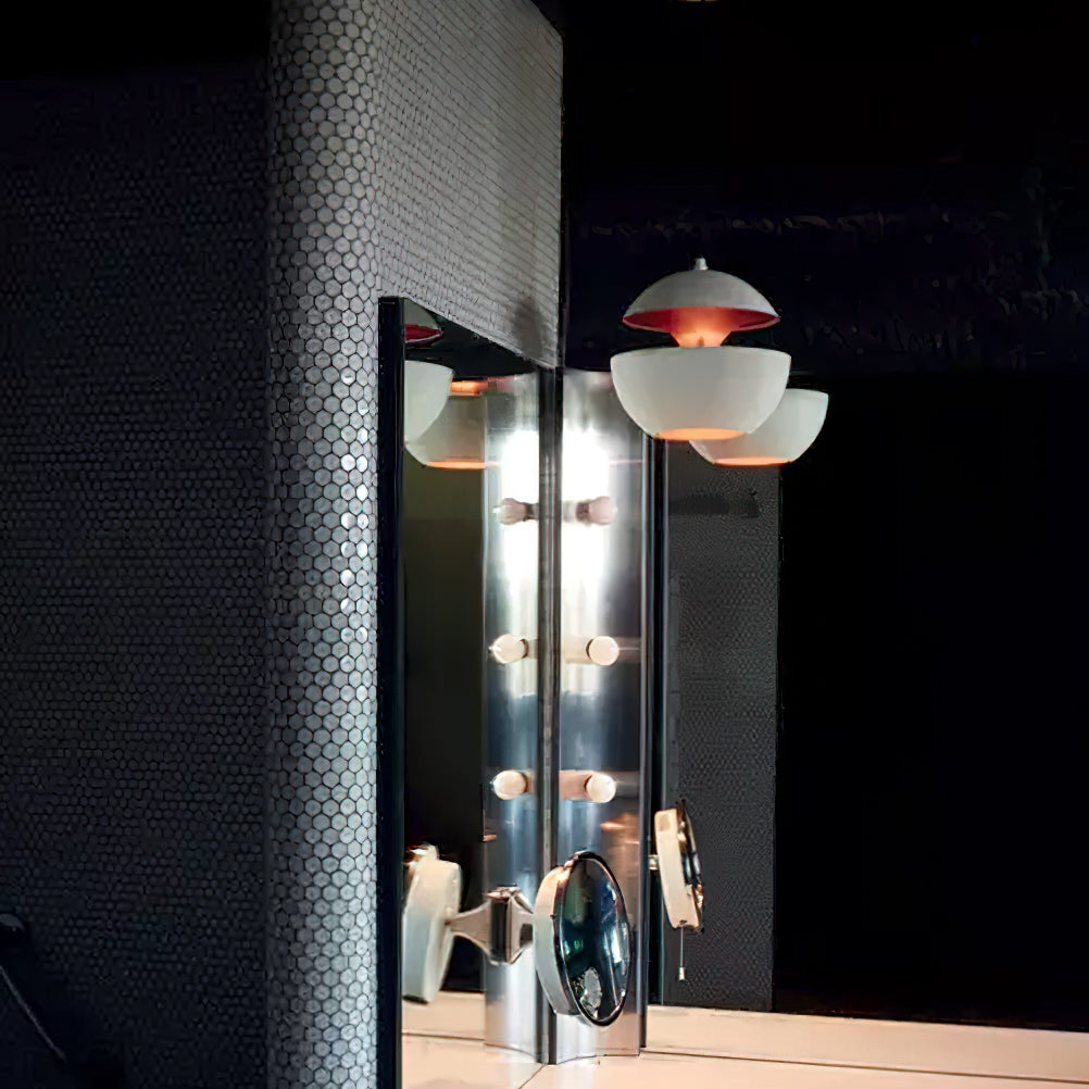 White pendants with gold interiors reflected in a mirrored column in a dark room, lamps from Clérachic.