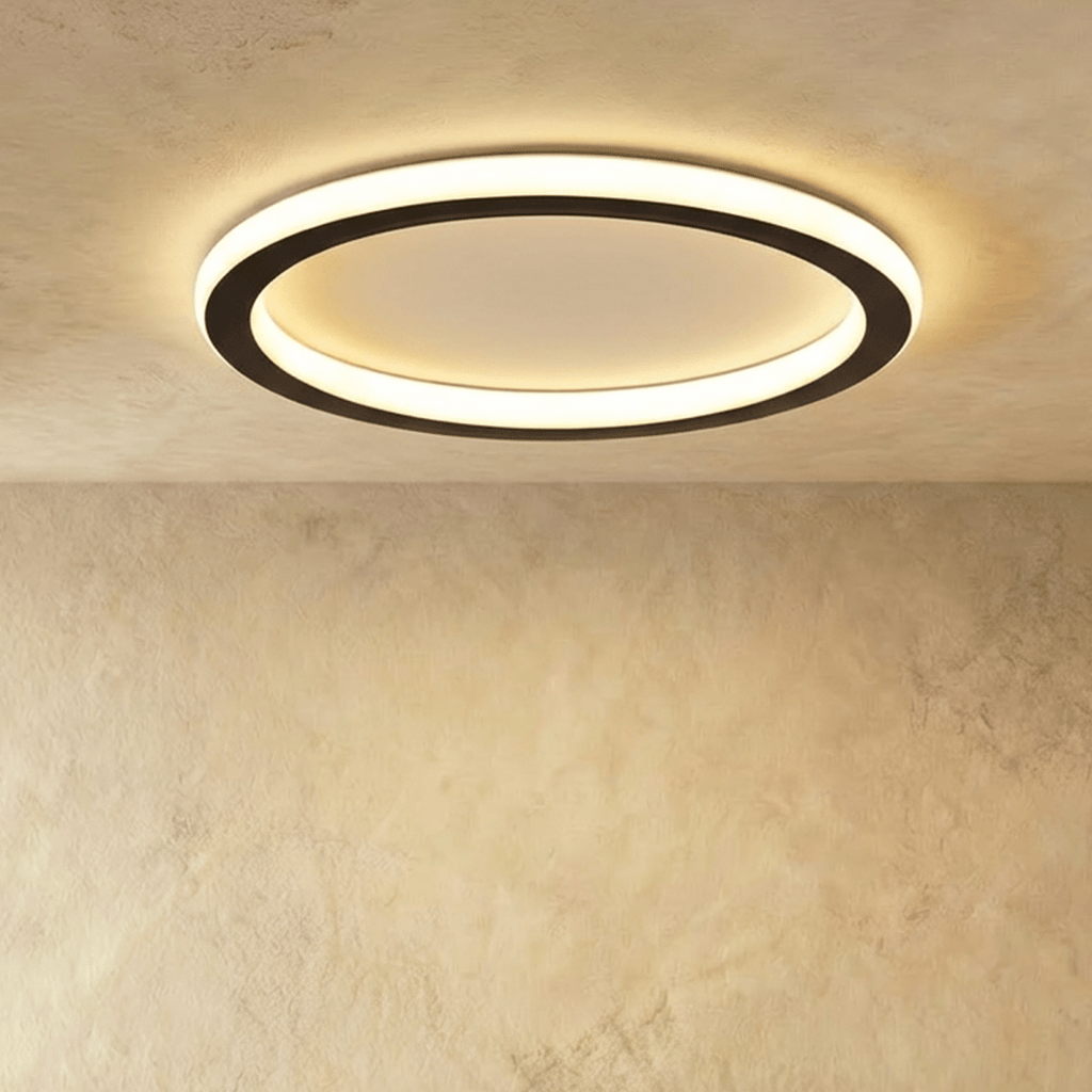 Clérachic slim round ceiling ring with a black outer band and a frosted white glowing halo, lit against a plastered ceiling.