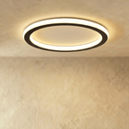 Clérachic slim round ceiling ring with a black outer band and a frosted white glowing halo, lit against a plastered ceiling.