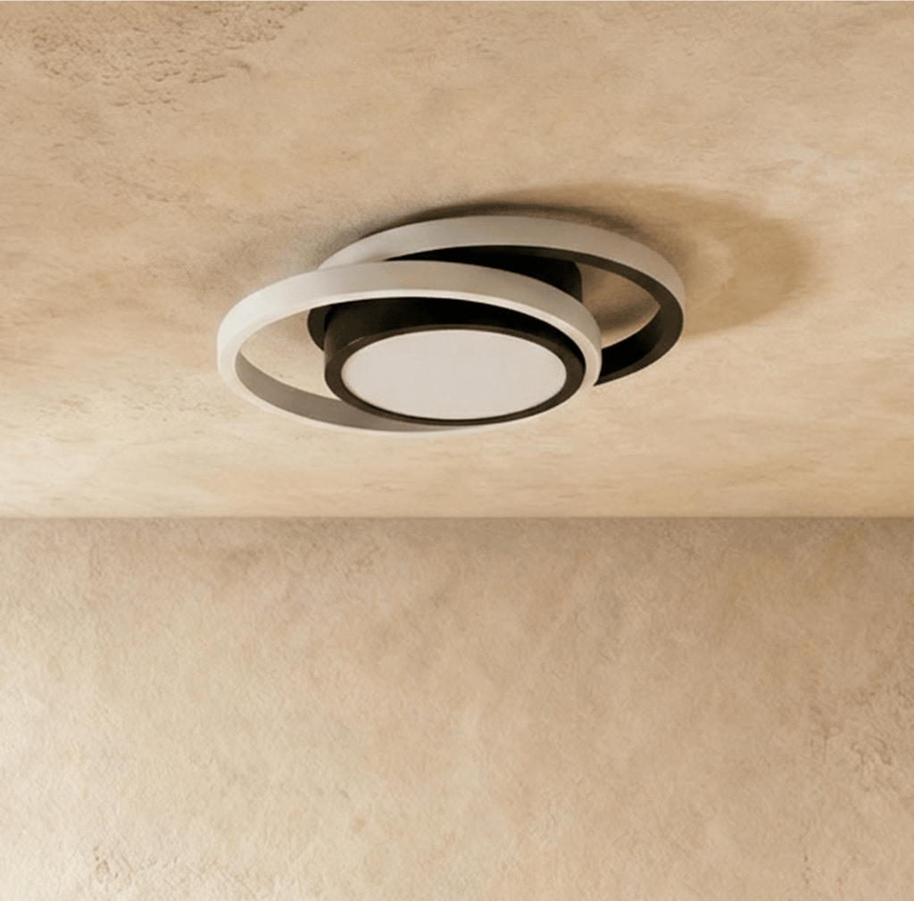Clérachic ceiling light with two offset white rings around a black round core, shown unlit on a limewash ceiling.