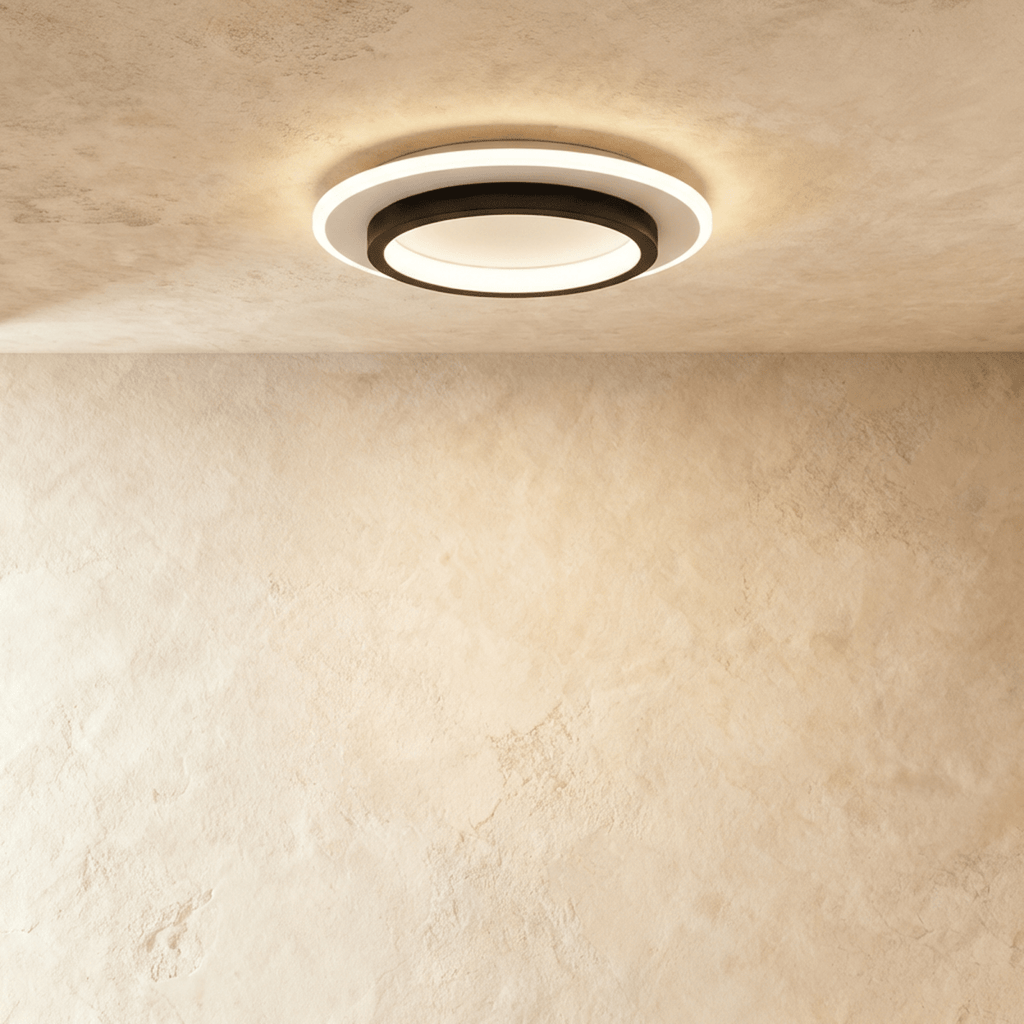 Clérachic round flush ceiling light with a black ring set inside a white acrylic disc, lit warm on a limewash ceiling.