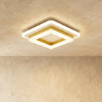 Clérachic stacked square ceiling light with a gold-finish frame and frosted white acrylic tiers, glowing warm on a ceiling.