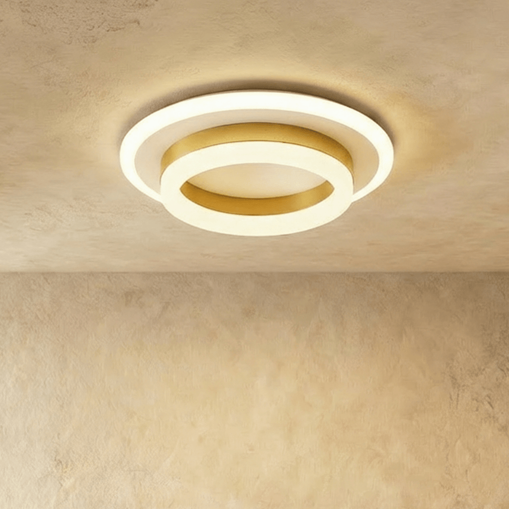 Clérachic two-tier round ceiling light with a gold-finish ring and frosted white acrylic, lit warm on a limewash ceiling.
