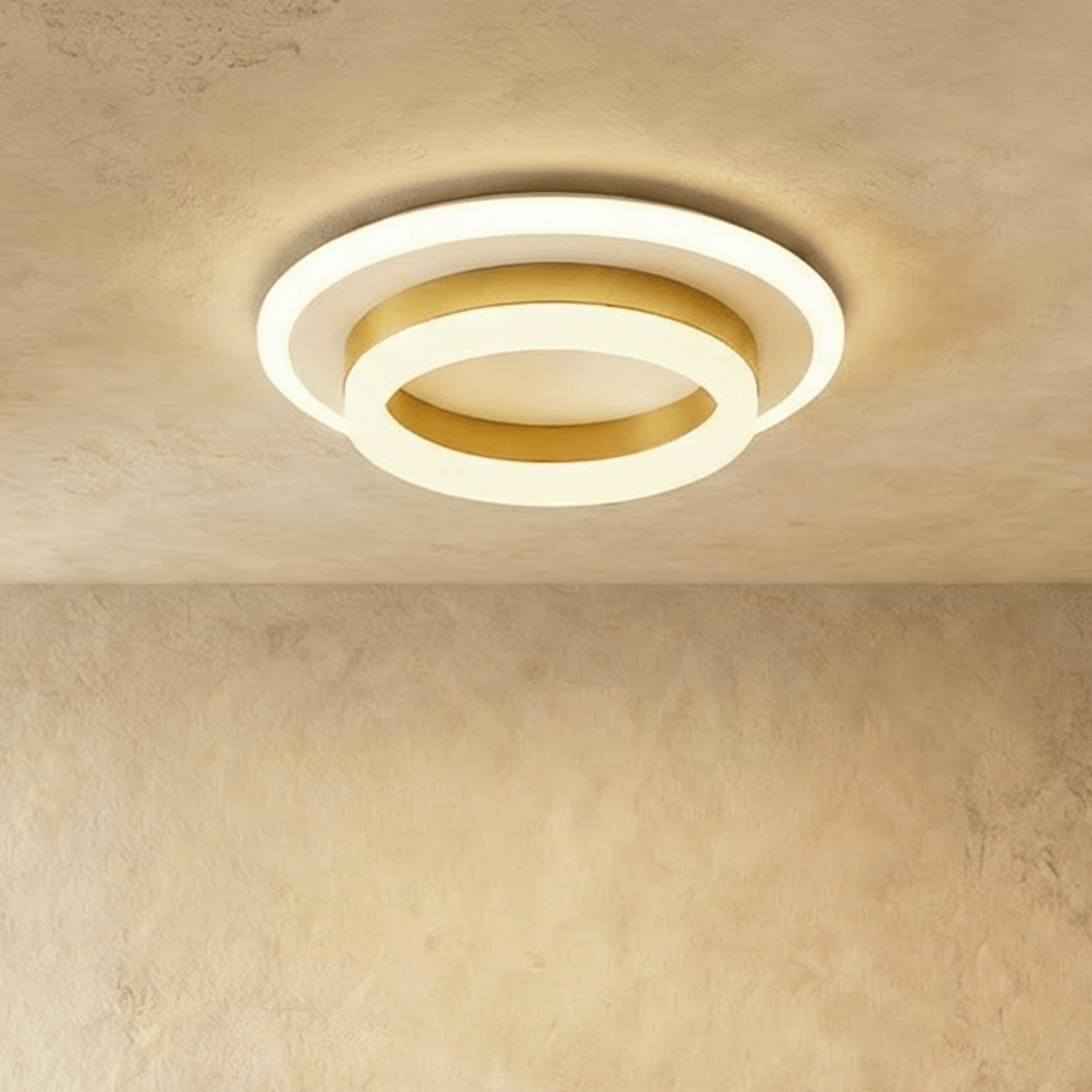 Clérachic two-tier round ceiling light with a gold-finish ring and frosted white acrylic, lit warm on a limewash ceiling.