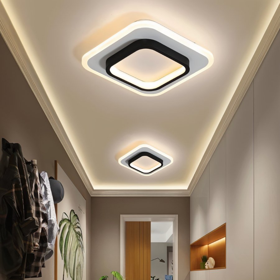 Two Clérachic square ceiling lights in black and white acrylic, in different sizes, glowing along a hallway with a coved ceiling.