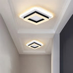 Two Clérachic square black and white ceiling lights in graduated sizes, lighting a panelled hallway ceiling with warm light.
