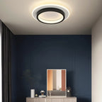 A Clérachic round black and white ceiling light glowing warm above a navy panelled wall, sideboard and framed print.