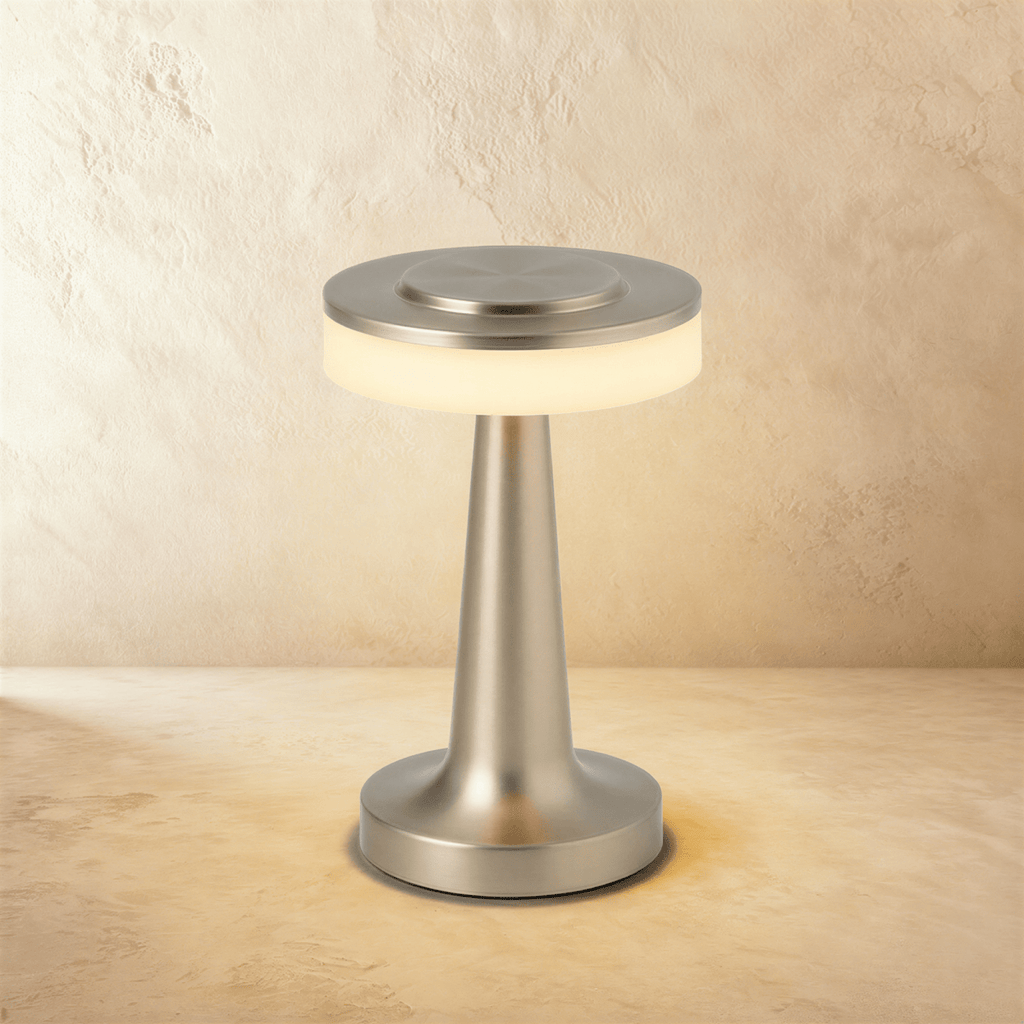 Clérachic cordless table lamp in satin silver, lit, a slim tapered stem rising from a round base to a disc head