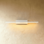 Clérachic mid-length white bar wall light with a warm lit arm, mounted on a plain white backplate against limewash.