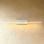 Clérachic long white bar wall light lit warm along its full length, on a rectangular backplate against a limewash wall.