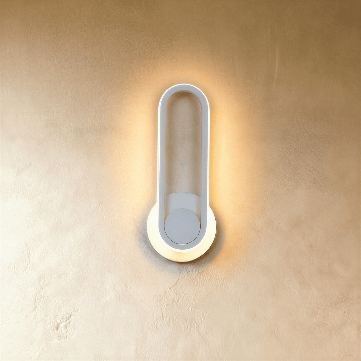 Clérachic white oval ring wall light, its edge glowing warm over a round white backplate on a limewash wall.
