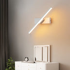 Clérachic white bar wall light angled diagonally above a white chest of drawers, throwing warm light across the wall.