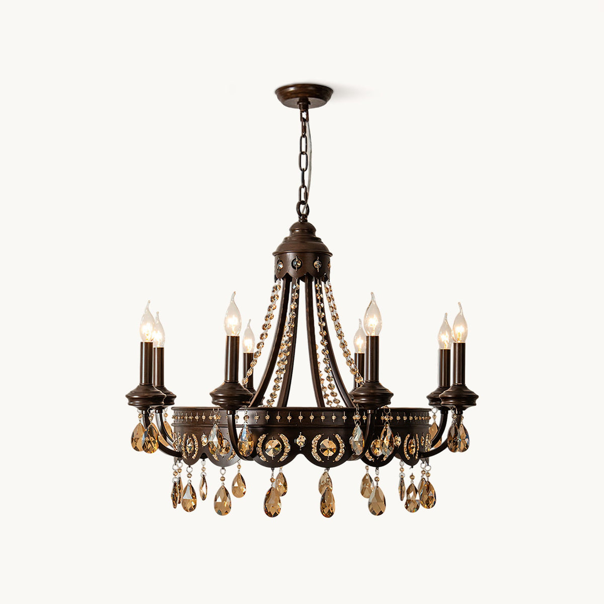 A Clérachic candle-style chandelier with a bronze-finish iron frame and amber crystal drops, hung on a chain against a white backdrop.